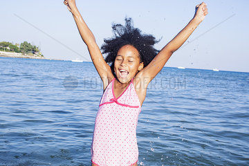 Girl in water raising arms with excitement