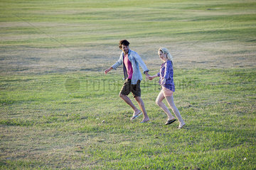 Couple running together in field  holding hands