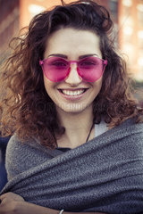 Woman wearing pink sunglasses  smiling cheerfully  portrait