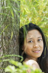Woman leaning against tree trunk  portrait