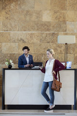 Woman looking at smartphone while waiting at reception desk