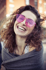 Woman wearing pink sunglasses  laughing  portrait