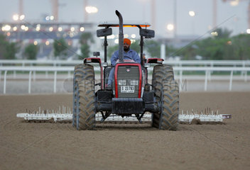 Dubai  VAE  Mann eggt das Sandgelaeuf der Galopprennbahn Nad al Sheba