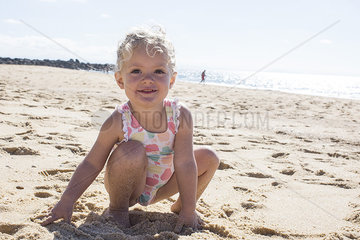 Little girl playing with sand on beach