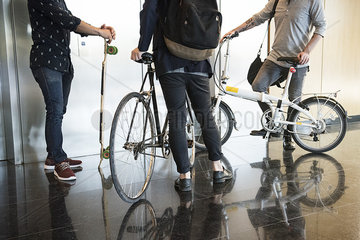 Men waiting for elevator with bicycles and longboard  low section