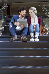 Couple sitting on steps  using digital tablet