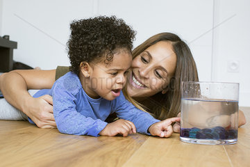 Mother and toddler daughter looking at pet goldfish