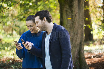 Couple using smartphones while walking in woods