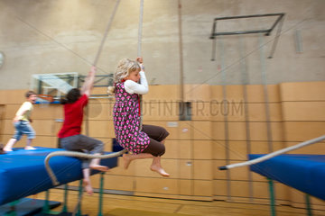 Berlin  Deutschland  blondes Maedchen schwingt auf einem Seil in einer Turnhalle