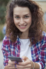 Young woman using smartphone  smiling  portrait