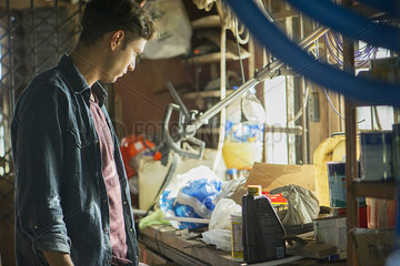 Man searching through cluttered attic for misplaced item