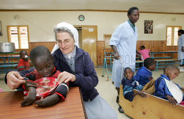 Kenia  eine katholische Schwester hilft einem koerperbehinderten Jungen beim Essen