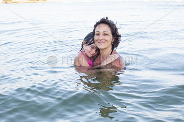Mother and daugther wading in sea