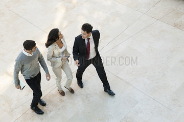 Business associates talking while walking together in office lobby