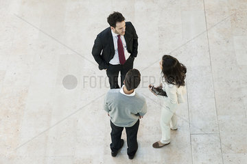 Business manager talking to associates in office lobby