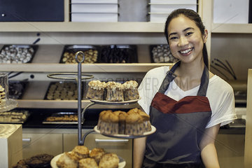 Woman smiling behind bakery counter  portrait