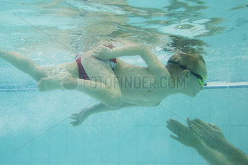 Boy swiming towards parent underwater
