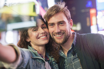 Young couple taking selfie in illuminated city street