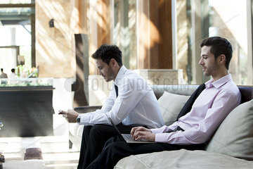 Businessmen using wireless devices in waiting room