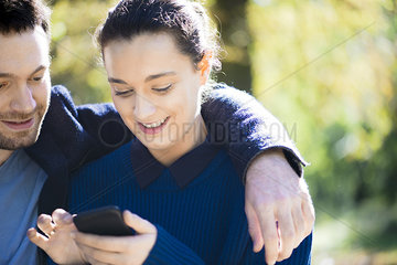 Couple using smartphone in woods