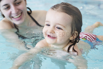 Little girl learning to swim with help of parent