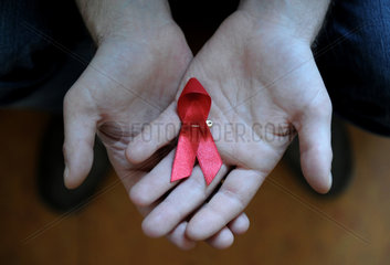 Berlin  Deutschland  Rote Schleife in den Haenden eines AIDS-kranken