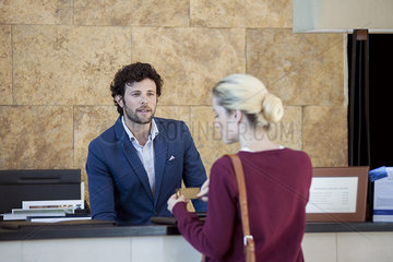 Hotel receptionist assisting guest