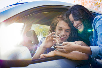 Couple looking for directions on smartphone before embarking on road trip
