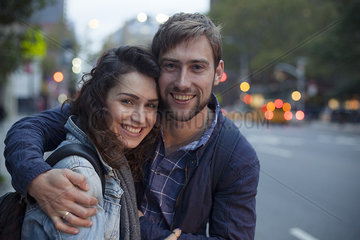 Young couple embracing on city street at night  portrait