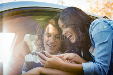 Couple looking for directions on smartphone before embarking on road trip