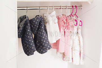 Baby clothes hanging in closet