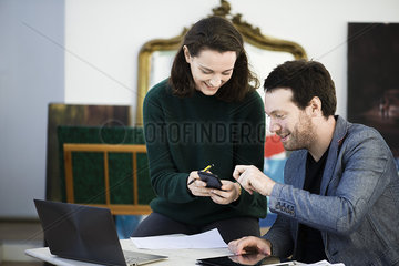 Woman sharing content of smartphone with colleague