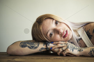 Tattooed woman resting head on arms  portrait