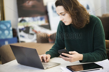 Woman multi-tasking with the help of laptop computer  digital tablet and smartphone