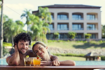 Couple relaxing with cocktails in resort pool