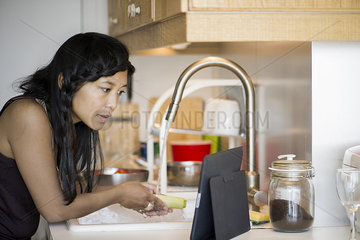 Woman using digital tablet while preparing food at home