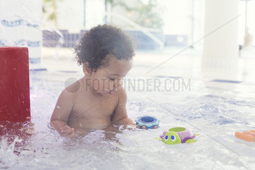 Little girl playing with toys in wading pool