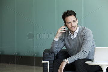 Businessman using cell phone and laptop computer