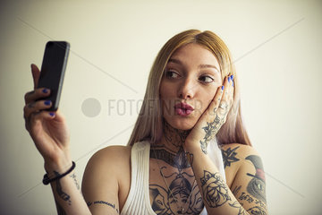 Tattooed woman taking selfie with smartphone