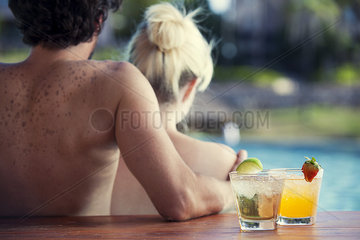 Couple relaxing at poolside with cocktails