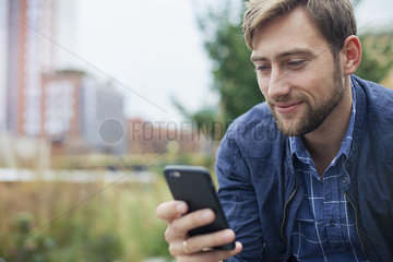 Man relaxing in park  looking at multimedia smartphone