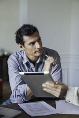 Man listening as colleague shows him something on a digital tablet