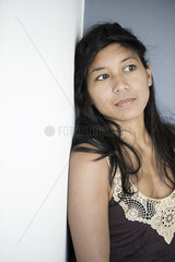 Woman leaning against wall  looking away in thought