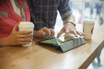 Couple using digital tablet in coffee shop  cropped
