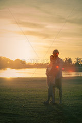 Couple standing together in park  bathed in sunlight