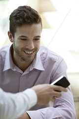 Office worker showing colleague content on smartphone