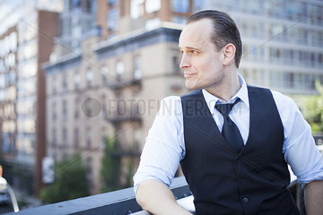 Businessman standing on balcony  looking away in thought