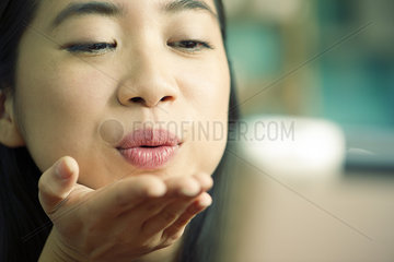Young woman blowing kiss at camera while video conferencing