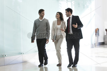 Business associates talking while walking together in office