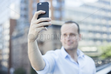 Man using smartphone to take a selfie